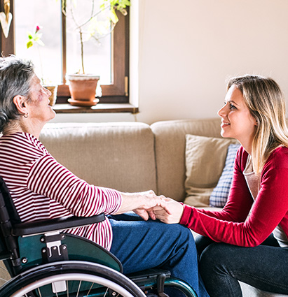 a woman smiling in a wheelchair with another woman standing behind her in a hallway representing care support and community empowerment six moments of connection